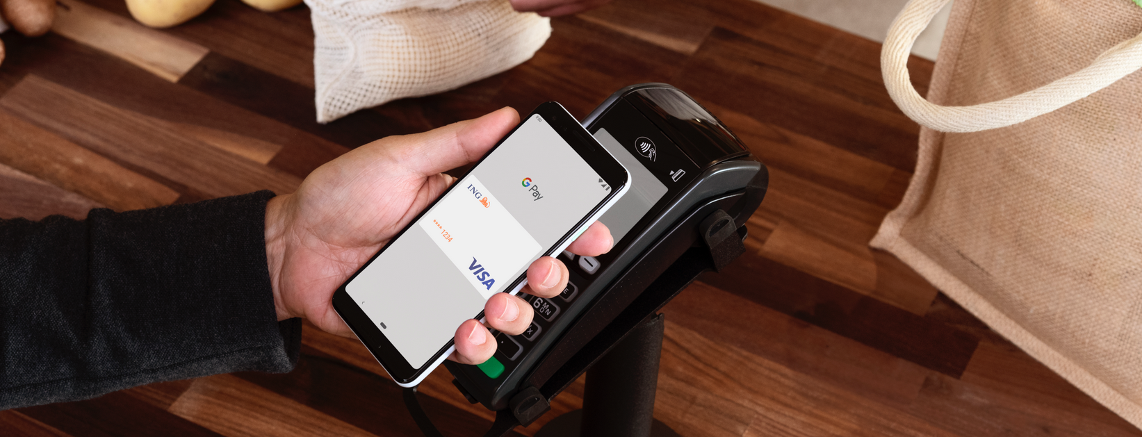 Smartphone mit Google-Pay-Anzeige wird an Kartenleser gehalten.